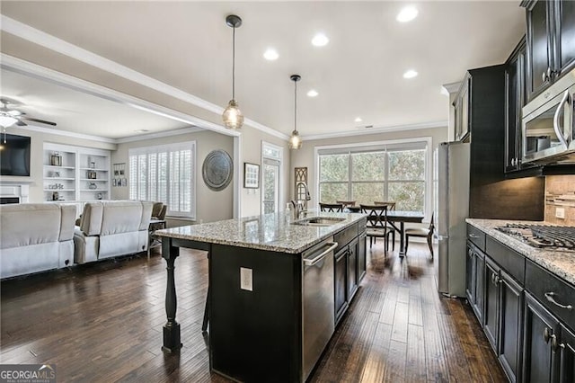 kitchen with an island with sink, sink, a kitchen breakfast bar, hanging light fixtures, and stainless steel appliances