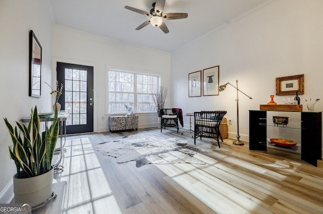 living area with ornamental molding, ceiling fan, and light wood-type flooring