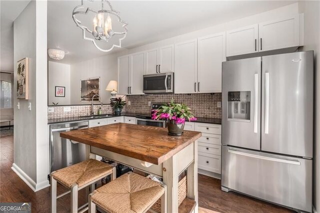 kitchen featuring sink, white cabinets, wooden counters, a chandelier, and stainless steel dishwasher