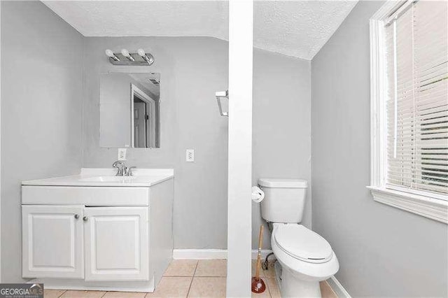 bathroom featuring vanity, a textured ceiling, vaulted ceiling, tile patterned floors, and toilet