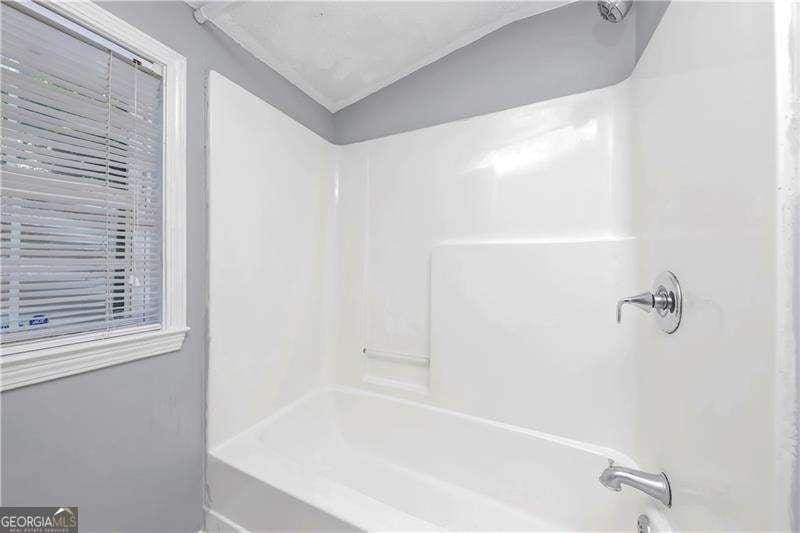 bathroom with lofted ceiling and washtub / shower combination