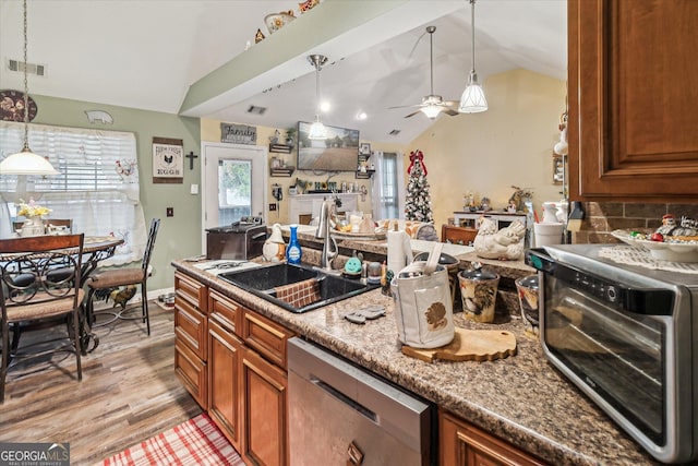 kitchen with stainless steel dishwasher, lofted ceiling, decorative light fixtures, and sink