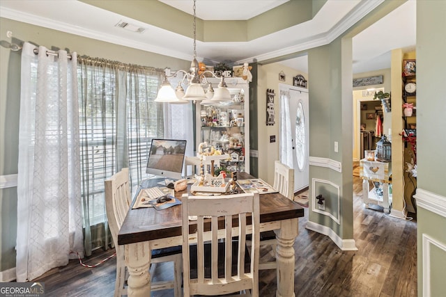 dining space featuring an inviting chandelier, ornamental molding, a tray ceiling, and dark hardwood / wood-style flooring