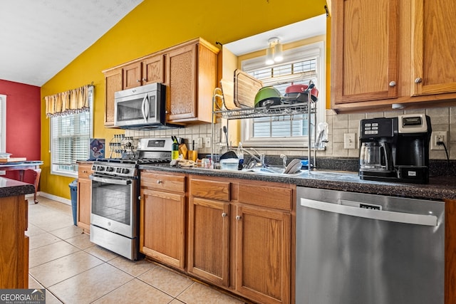 kitchen with backsplash, lofted ceiling, appliances with stainless steel finishes, and light tile patterned floors