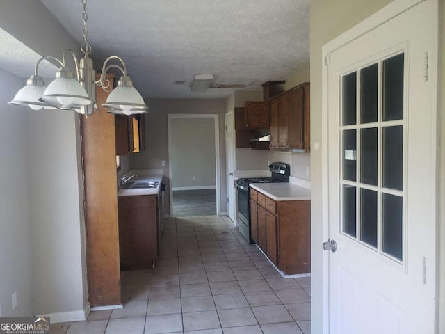 kitchen featuring decorative light fixtures, sink, light tile patterned floors, stainless steel range, and a textured ceiling