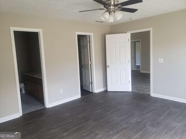 unfurnished bedroom featuring ceiling fan, ensuite bath, dark hardwood / wood-style flooring, and a closet