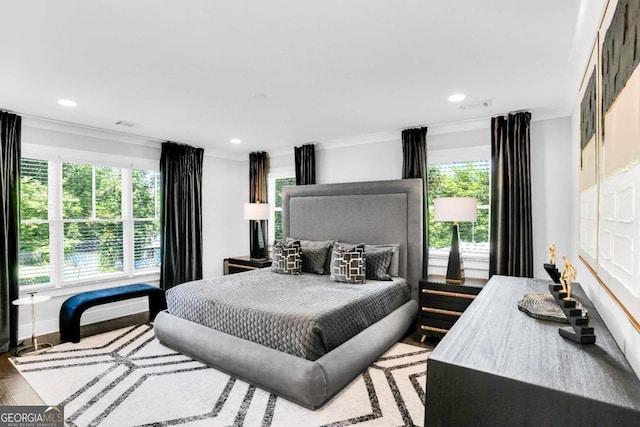 bedroom featuring multiple windows, ornamental molding, and light hardwood / wood-style floors