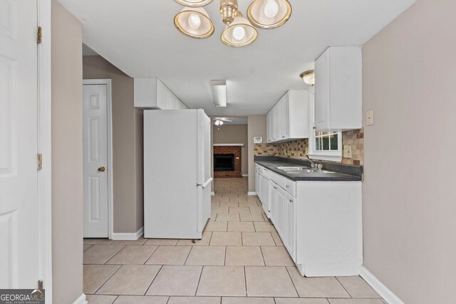 kitchen with white cabinetry, backsplash, sink, and white fridge