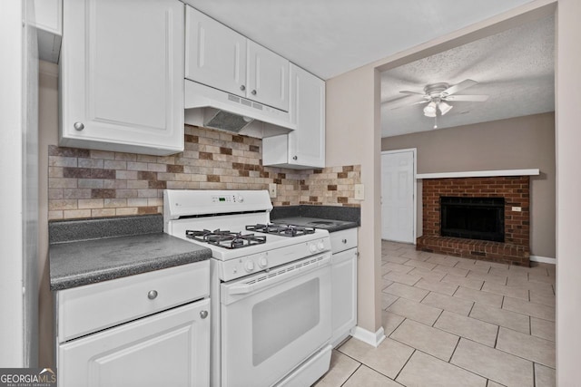 kitchen featuring a fireplace, white cabinets, white range with gas stovetop, ceiling fan, and a textured ceiling