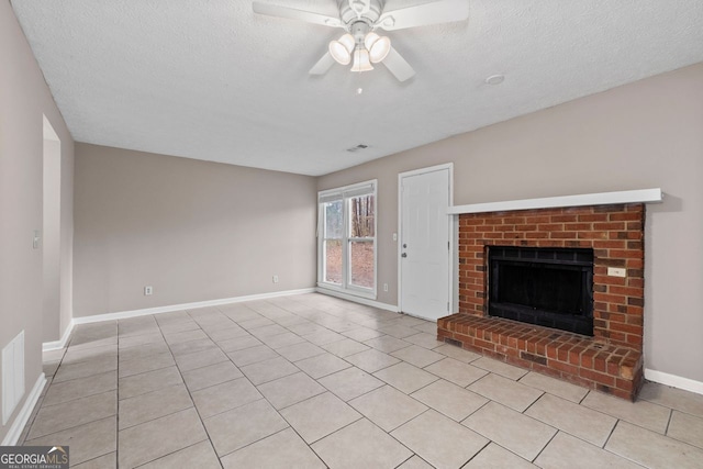 unfurnished living room featuring a brick fireplace, light tile patterned floors, a textured ceiling, and ceiling fan