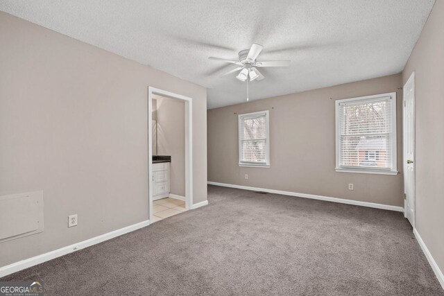 unfurnished bedroom with multiple windows, light carpet, a textured ceiling, and ceiling fan