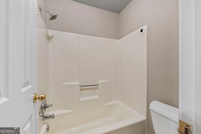 bathroom with shower / tub combination, toilet, and a textured ceiling