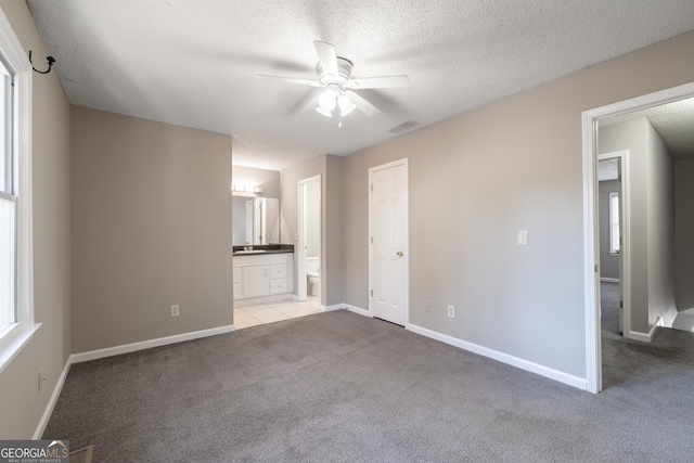 unfurnished living room with ceiling fan, light colored carpet, and a textured ceiling