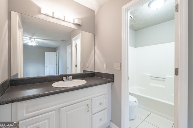 full bathroom with ceiling fan, vanity, a textured ceiling, tile patterned floors, and toilet