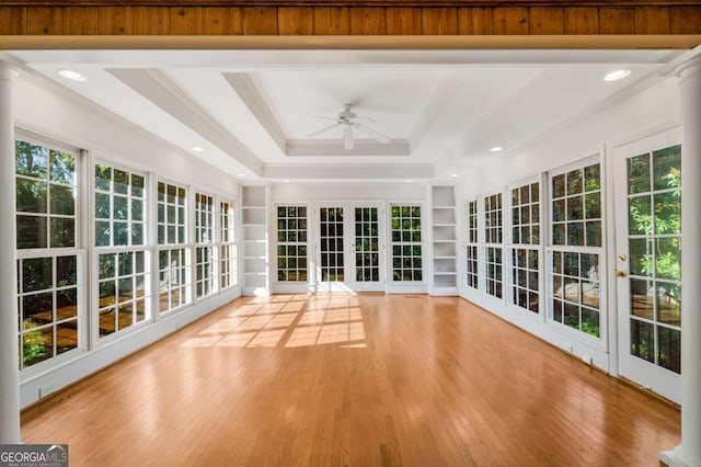 unfurnished sunroom featuring a raised ceiling and ceiling fan