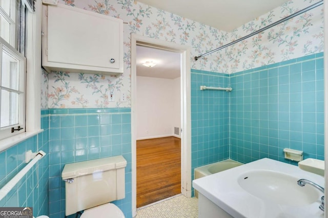 full bathroom featuring washtub / shower combination, tile patterned floors, toilet, sink, and tile walls