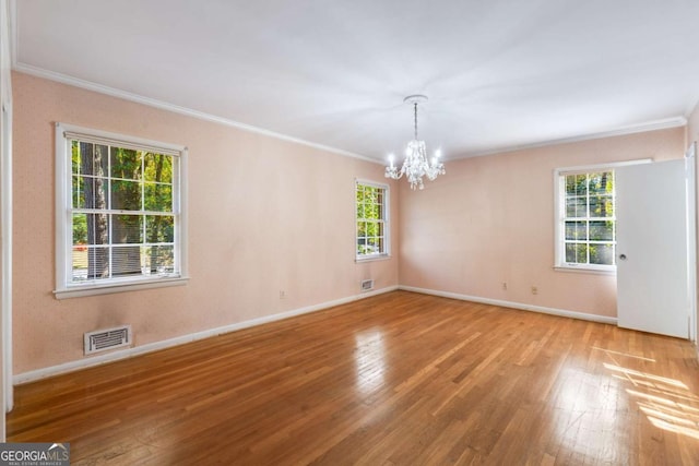 empty room with ornamental molding, light hardwood / wood-style flooring, and a notable chandelier