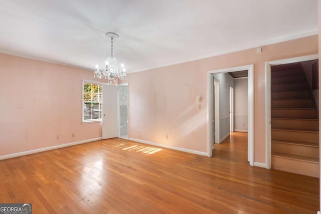 spare room with crown molding, wood-type flooring, and a notable chandelier