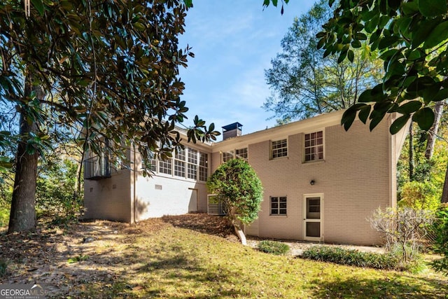 rear view of house with a sunroom and a lawn