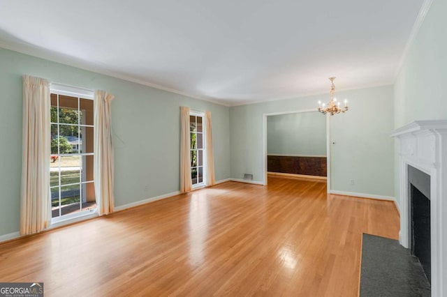 unfurnished living room with a notable chandelier, crown molding, and light hardwood / wood-style floors