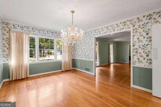 unfurnished dining area featuring a notable chandelier, crown molding, and wood-type flooring