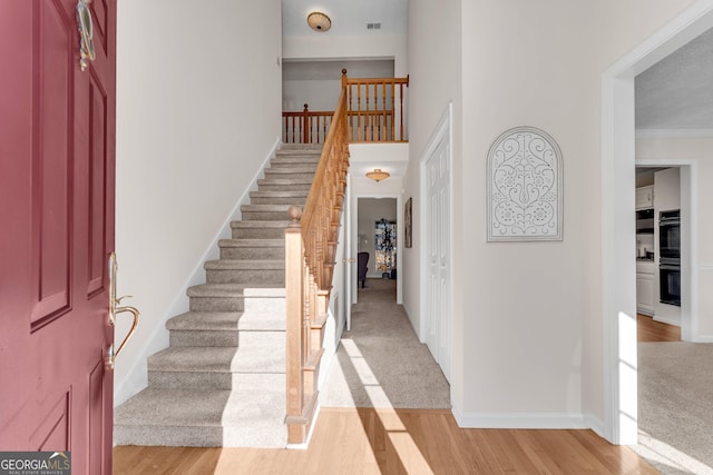 entrance foyer with ornamental molding and light hardwood / wood-style flooring