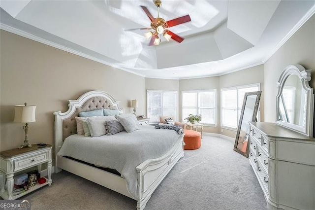 carpeted bedroom featuring a raised ceiling, ornamental molding, and ceiling fan