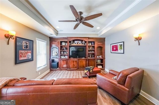 living room with crown molding, ceiling fan, a raised ceiling, and light hardwood / wood-style flooring