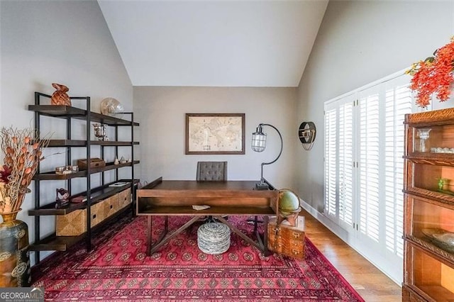 home office with vaulted ceiling and hardwood / wood-style floors