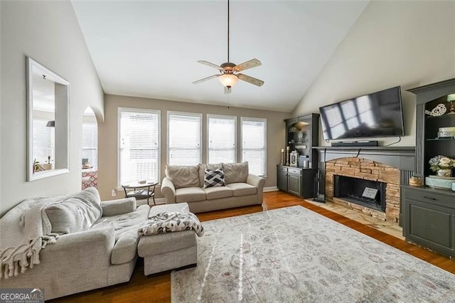 living room featuring hardwood / wood-style floors, a fireplace, high vaulted ceiling, and ceiling fan