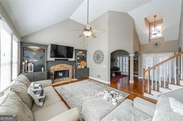 living room with a fireplace, decorative columns, hardwood / wood-style flooring, ceiling fan, and built in shelves