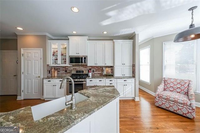 kitchen featuring appliances with stainless steel finishes, dark stone countertops, and white cabinets