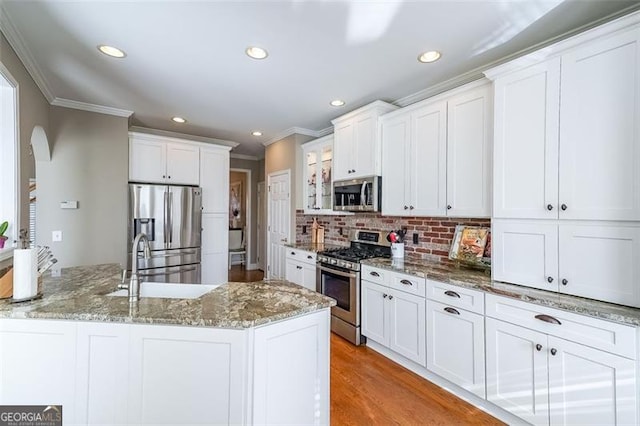 kitchen featuring white cabinetry, backsplash, stainless steel appliances, and light stone countertops