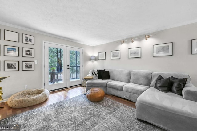 living room with hardwood / wood-style flooring, ornamental molding, a textured ceiling, and french doors