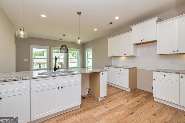 kitchen with white cabinetry, sink, tasteful backsplash, and pendant lighting