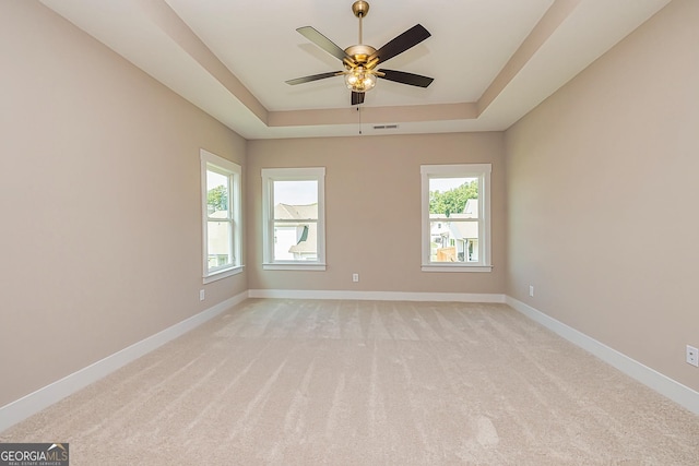 carpeted spare room featuring a raised ceiling and ceiling fan