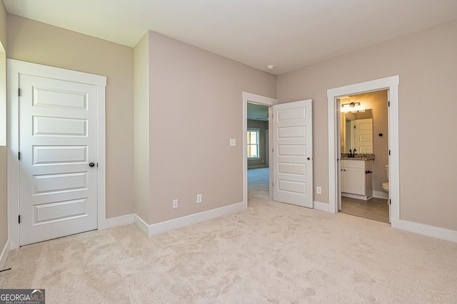 unfurnished bedroom featuring light carpet and ensuite bathroom