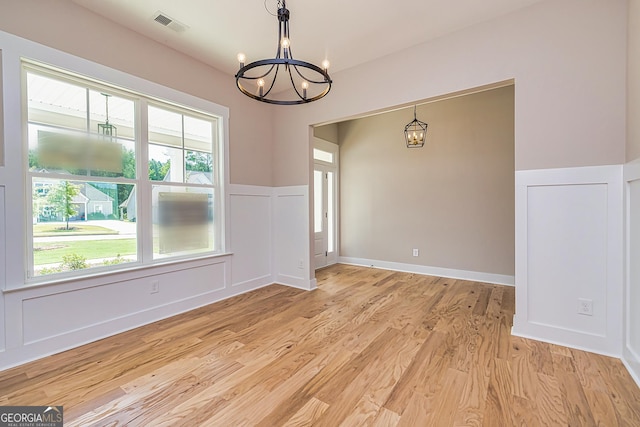 unfurnished dining area featuring a notable chandelier and light wood-type flooring