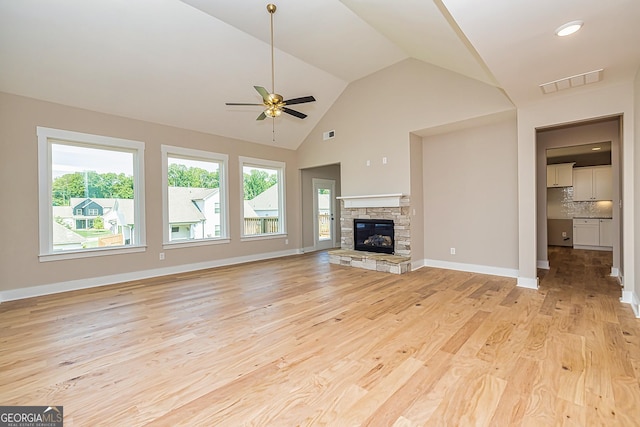 unfurnished living room featuring ceiling fan, lofted ceiling, a fireplace, and light hardwood / wood-style floors