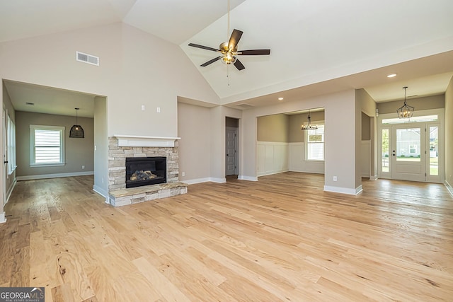 unfurnished living room with ceiling fan, high vaulted ceiling, a fireplace, and light hardwood / wood-style floors