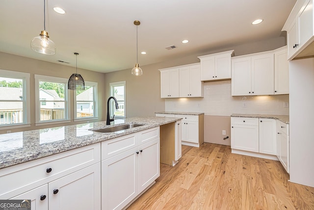 kitchen featuring sink, hanging light fixtures, and white cabinets