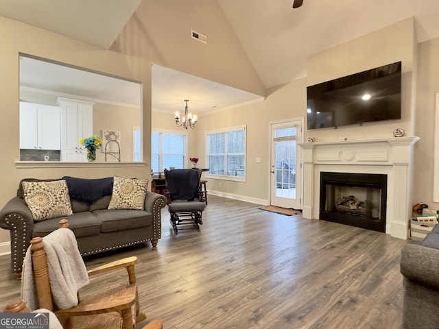 living room with an inviting chandelier, hardwood / wood-style floors, ornamental molding, and high vaulted ceiling