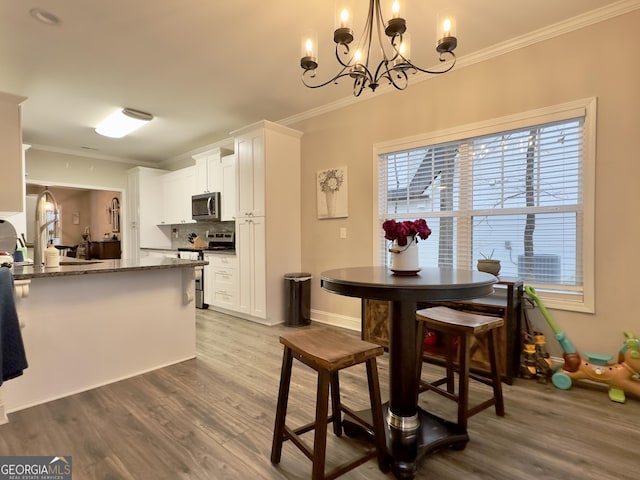 dining space with ornamental molding, sink, a notable chandelier, and light hardwood / wood-style floors