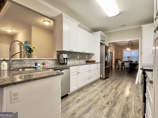 kitchen featuring white cabinetry, decorative backsplash, light hardwood / wood-style flooring, and appliances with stainless steel finishes