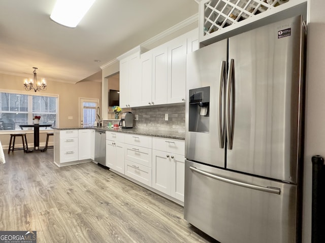 kitchen with hanging light fixtures, stainless steel appliances, white cabinets, decorative backsplash, and kitchen peninsula