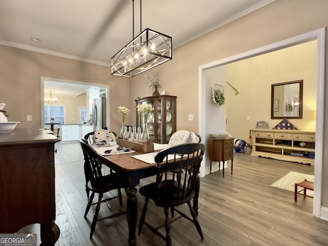 dining area featuring an inviting chandelier, crown molding, and hardwood / wood-style flooring