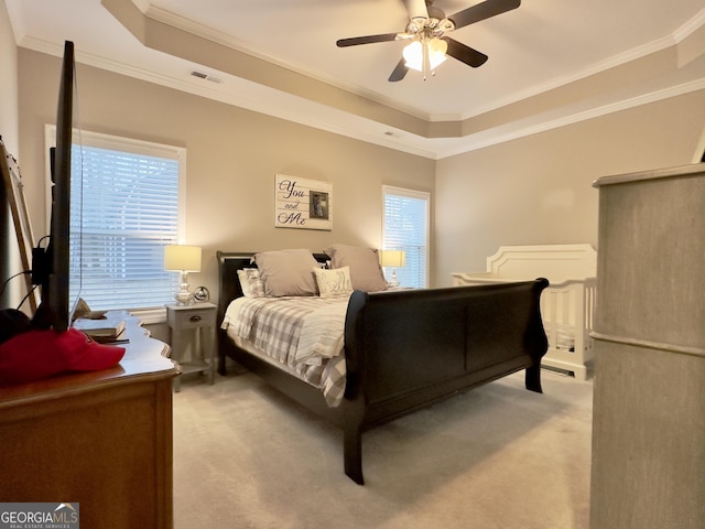 carpeted bedroom featuring ceiling fan, ornamental molding, and a tray ceiling