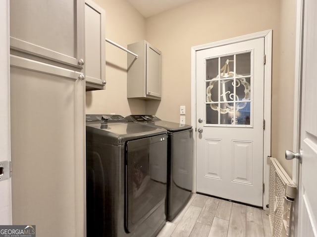 laundry area with cabinets, separate washer and dryer, and light hardwood / wood-style flooring