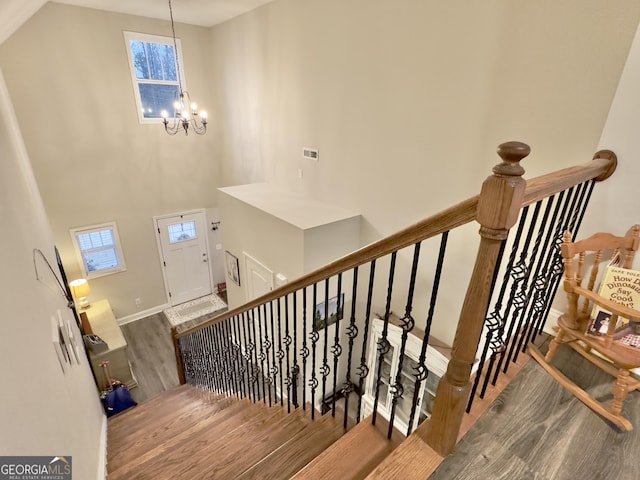 staircase with a notable chandelier and hardwood / wood-style floors