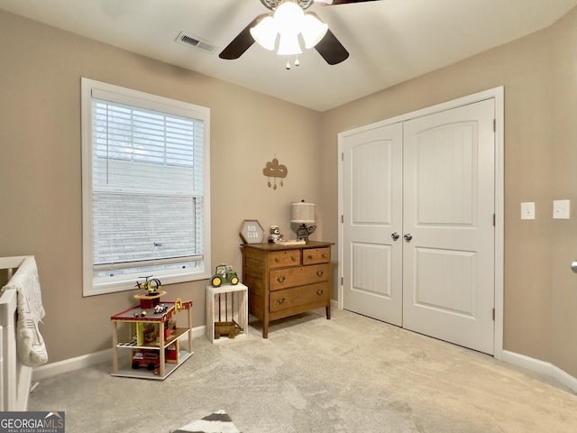 carpeted bedroom with ceiling fan and a closet